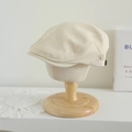 Detailopname van beige platte pet met zijknoop op een houten mannequinkop - 52-54cm / Broken Wit