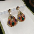 Dettaglio macro di orecchini a goccia vintage dorati con cristalli colorati e box - Ago d'argento / Oro-Multicolore