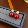 Elegant gold-plated stud earrings with dark red pearls and sparkling cubic zirconia stones - Red Bead Stud Earrings / Gold with Red
