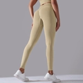 Detailansicht der beigen nahtlosen Yogahose mit pfirsichfarbenem Push-up-Effekt - Hellkamel