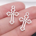Two silver cross pendants for DIY jewelry making shown on a hand for scale - Hollow 19x12mm (0.5g)