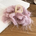 Vue détaillée d'une pince à cheveux lavande avec fleurs en tissu et pompons soyeux - Grande Pince à Requin à Glands en Maille Violette