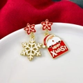 Makroaufnahme asymmetrischer Weihnachtsohrringe mit Schneeflocke und Weihnachtsmann - Stern Schneeflocke & Schneemann