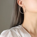 Orecchini a cerchio intrecciati in acciaio al titanio argento indossati da modella - Grandi Orecchini in Acciaio / Diametro 3,6 cm