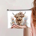 White Highland cow makeup bag with floral bow print held by a model in a floral dress - Highland Cow with Pink Floral Bow (jiayingpbb0106)