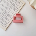 Pink rectangular matte hair claw clip on an open book showing a minimalist hollow design - Matte Pink