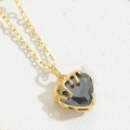 Macro shot of gold heart necklace with black zircon and liquid metal style detail - Black