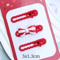 Close-up of three red macaron clips including a festive bow hair clip on a card - 1.2x4.9cm / New Year Red
