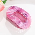 Close-up of a pink marble pattern plastic claw clip with a hollow oval design - Rose Red Smudge