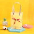 Macro detail of a yellow bear-shaped towel gift in a clear PVC bag with a red ribbon decoration - Yellow