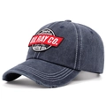 Detail of vintage blue washed cotton baseball cap with retro motor oil embroidery and worn brim - Lotus Pink