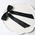 Elegant black satin hair clip with long ribbons on a white decorative ceramic tray - Black