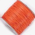 Detailed macro view of vibrant orange waxed polyester cord on a roll for jewelry making - Orange