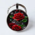 Detail view of round metal keychain with glass dome featuring a red rose and water drops - Waterdrop Red Rose/Silver Frame