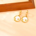 Détail de boucles d'oreilles créoles dorées en émail blanc avec motifs soleil et lune - Boucles d'Oreilles Étoile Lune Coquille Blanche