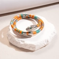 Vista dettagliata del bracciale a serpente arancione e turchese su una base di pietra bianca - Bracciale-Verde