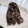 Dark brown faux cashmere scarf with fringes and minimalist label on soft plush background - Coffee