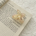 Detail view of a butterfly acetate hair claw clip with floral patterns on a vintage book - Pink Multicolor