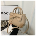 Close-up of beige bow handbag with matte PU texture and elegant curved top handles - Khaki