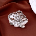 Gros plan d'une broche fleur argentée avec texture métallique sur satin luxueux - Argenté
