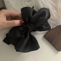 Detail shot of a large black satin bow hair claw clip with glossy silk texture - Black
