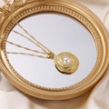 Elegant gold necklace with oval spiral pendant and white pearl on silk fabric - Necklace