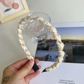 Detail view of a cream braided headband with beaded texture and elegant spiral ribbon finish - 210906 Beige