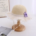 Detail of child straw hat featuring chiffon pleated brim and purple flower ornament - Beige