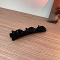 Detail of a black velvet hair clip with three 3D flower designs on a wooden surface - Black