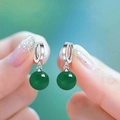 Elegante zilveren oorringen met natuurlijke groene agaat vastgehouden in de hand - Platina + Groene Agaat