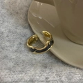 Detailaufnahme von vergoldetem Vintage-Emaille-Ring auf Keramikrand mit Strickhintergrund - Schwarz