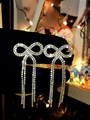 Silver bow rhinestone long tassel earrings shown in a festive hand-held close-up view - Gold Bow Tassel