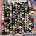 Hand holding a natural multi-color tourmaline round bead bracelet for DIY jewelry - Natural Tourmaline