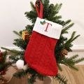Red knitted Christmas stocking with white cuff and embroidered letter T hanging on a tree - Letter T
