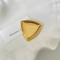 Polished gold-tone stainless steel triangular brooch pin on a decorative white plate - 8# Triangle Gold Brooch