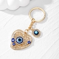 Detail eines herzförmigen Hohl-Schlüsselanhängers mit Goldauflage und Evil Eye Kristallen - Strass Auge / Goldenes Hohles Herz