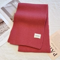 Thick red knitted winter scarf with minimalist brand label on a soft fabric background - Jasmine Pink