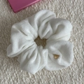 Close-up of white terry cloth scrunchie with a gold metal tag on knit background - Scrunchie / Cream