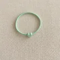 Detail of high-elasticity mint green hair tie featuring a matte heart-shaped charm - Green
