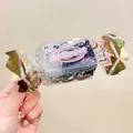 Macro detail of high elasticity disposable hair ties in a candy shaped plastic gift box - Transparent + Black