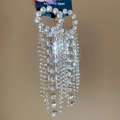 Détail de boucles d'oreilles longues à pampilles avec strass brillants et fini doré - Doré