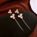 Dettaglio di orecchini lunghi dorati con fiori di strass e perle bianche su pietra - Oro