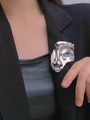 Close-up of surrealist silver face brooch with blue eye detail on black blazer suit - Silver Brooch