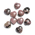 Macro shot of nine polished heart-shaped rhodonite stones with pink and black textures - Rhodonite