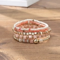 Boho-Armband-Set mit Perlen in Pink, Orange und Gold auf einem Holzsockel - B317-warme Farbe