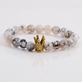 Detail of 8mm marble textured stone beads bracelet with a gold crown charm on reflective surface - White Marble Pattern