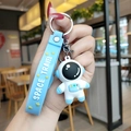 Cute white astronaut keychain with blue silicone strap and Space Travel text on a ring - Blue