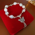 Primer plano de pulsera de cuentas de vidrio con mariposa y borlas en un joyero - Gris Plata