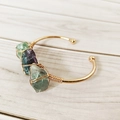 Detailed macro view of handmade copper wire wrap with natural green and purple fluorite stones - Fluorite