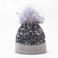 Detail van de zilveren pailletten en een pluizige grijze bontpompom op een wintergebreide muts - Eén maat / Grijs (Geverfde Pompon)